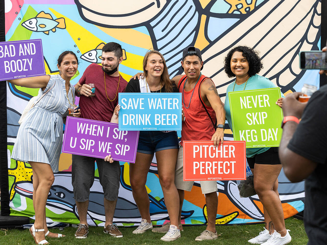 Group posing with punny signs during Coastal Craft Beer Festival