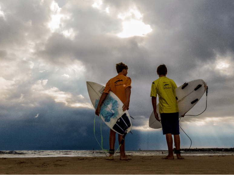 Two surfers looking out into water during Neptune's Surfing Classic