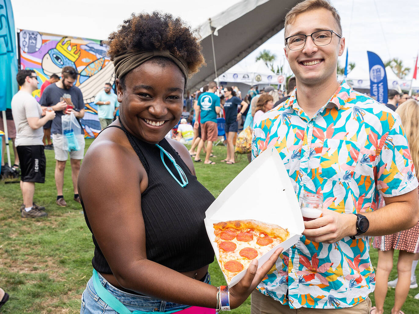 Couple posing with pizza and beer for photo during Coastal Craft Beer Festival