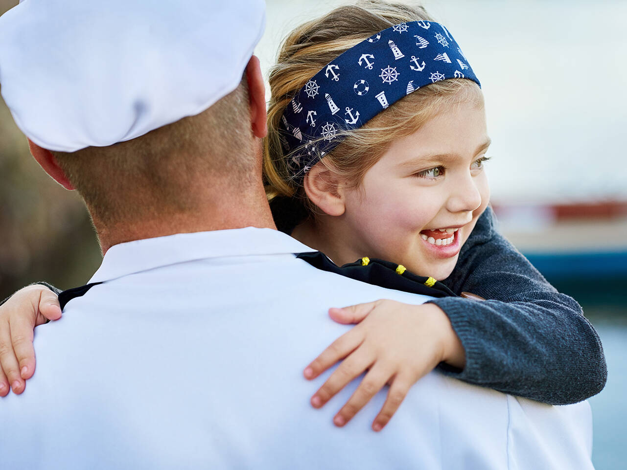 Young girl hugging dad in Navy uniform