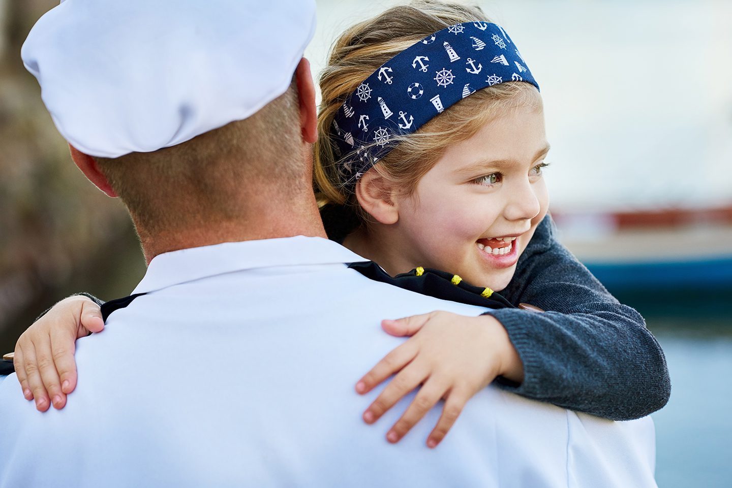 Young girl hugging dad in Navy uniform