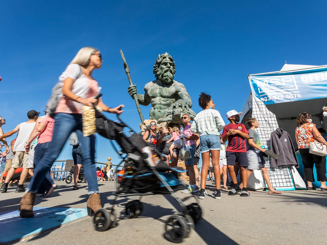 Group of people on boardwalk in front of Neptune statue