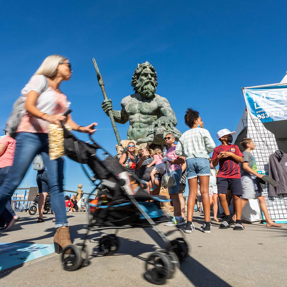 Group of people on boardwalk in front of Neptune statue