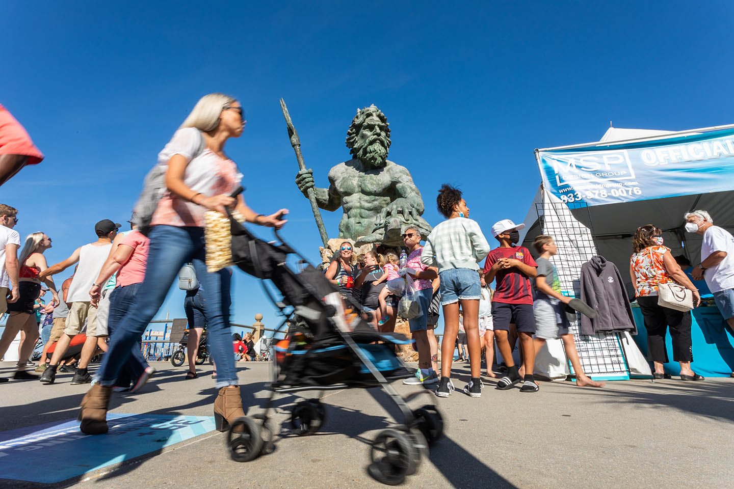 Group of people on boardwalk in front of Neptune statue